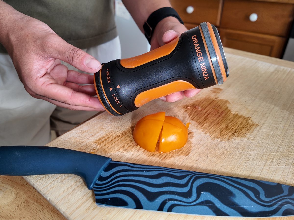 Orange Ninja knife sharpener in use on a cutting board